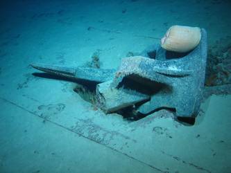 Stbd anchor embedded in steel plate from ship's side in debris field